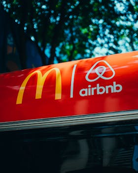 A vibrant red sign featuring logos of McDonald's and Airbnb in an urban setting.